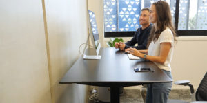 couple smiling at computer with dark standing desk