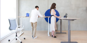man and woman standing at stand desks