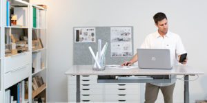 man working on laptop at stand desk