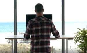 man in plaid shirt using standing desk